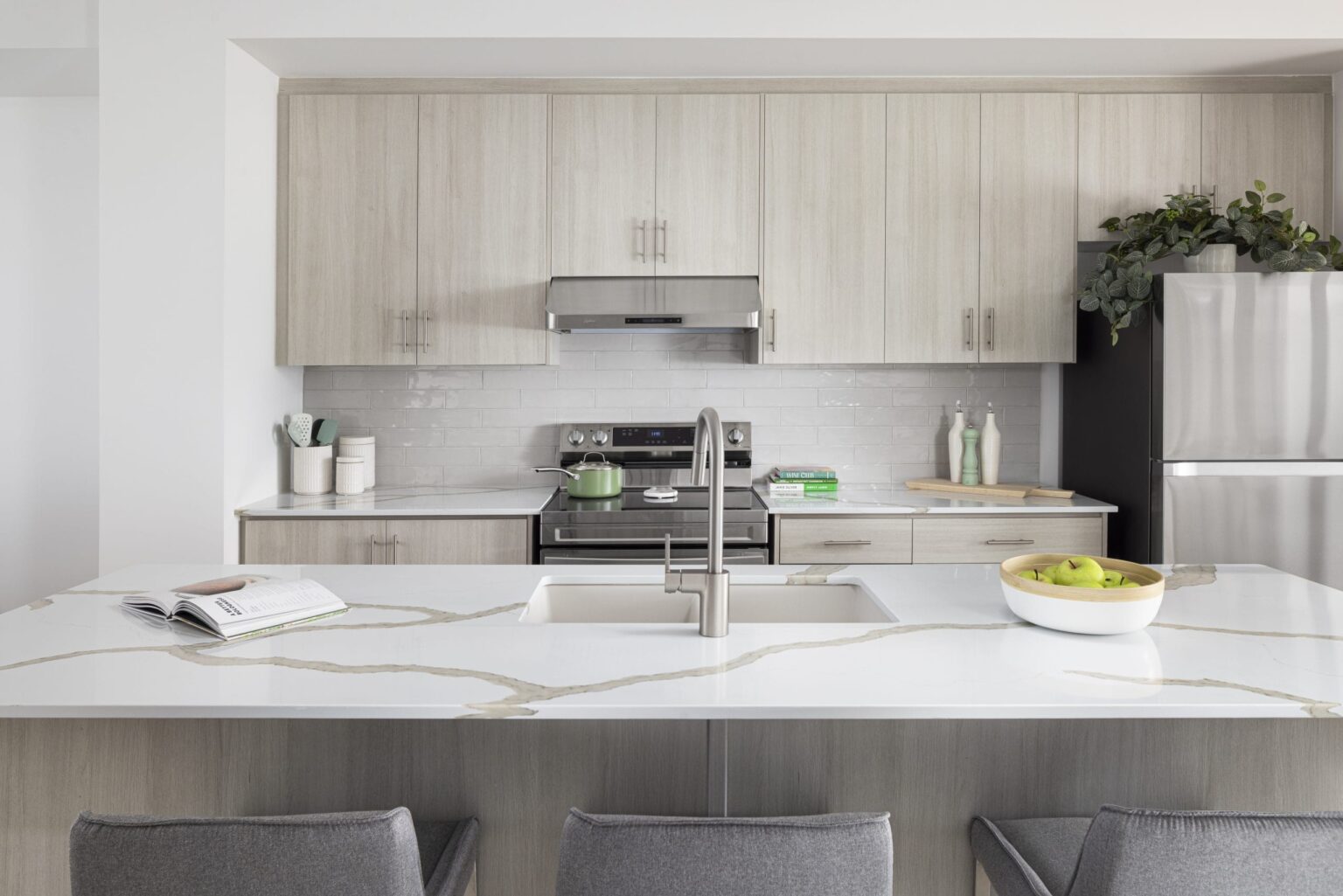 Kitchen with light wood cabinets, quartz island and stainless appliances
